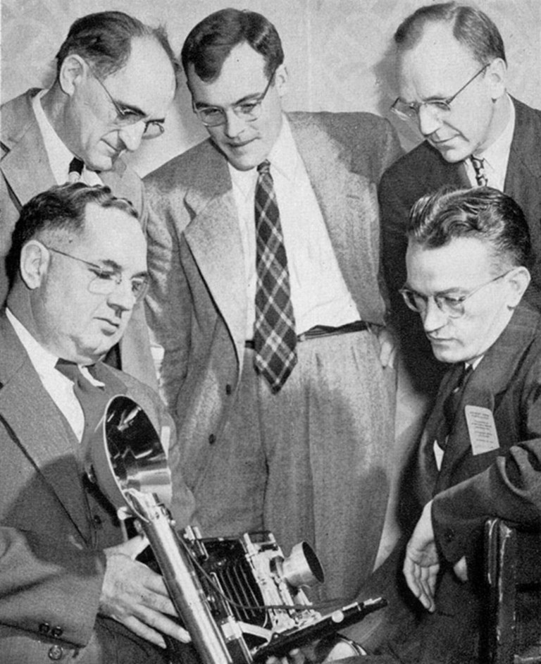 Men admiring a large format press camera