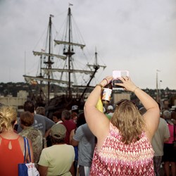 A Woman Takes A Smartphone Photo Of A Tall Ship